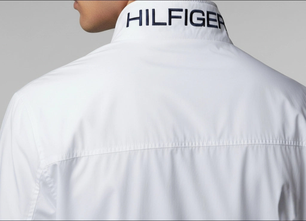 White shirt with 'Tommy Hilfiger' logo on the collar against a gray background