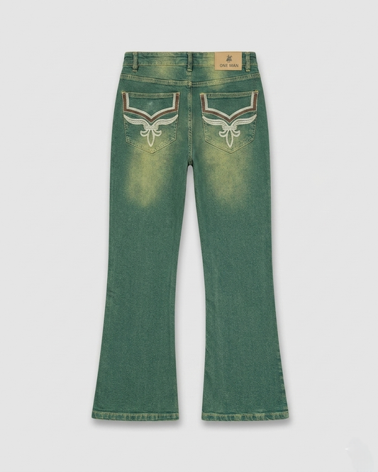 Green denim jeans with decorative stitching on a light gray background