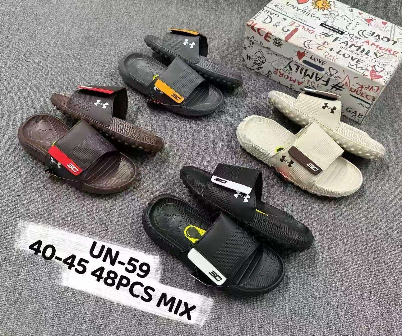 Collection of Under Armour slides on a gray surface with a branded box in the background. Main image