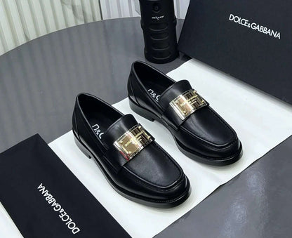 Black loafers with gold buckles on a Dolce & Gabbana branded box.