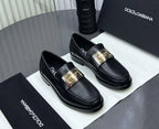 Black loafers with gold buckles on a Dolce & Gabbana branded box.