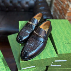 Black loafers on a green Gucci box with a blurred background