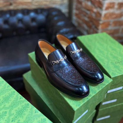 Pair of black loafers on green boxes with a brick wall and leather chair in the background