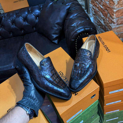 Black leather loafers on a Louis Vuitton box with brand packaging in the background.