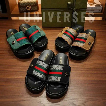 Pair of Gucci slides on a wooden surface with a box and other items in the background.