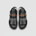 Black sandals with patterned straps on a wooden surface