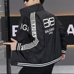 Person wearing a black jacket with branding on the back, pointing at the jacket.