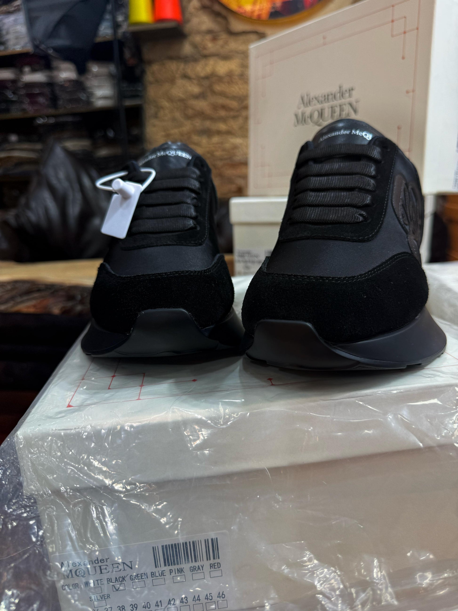 Front profile of the black Alexander McQueen Sprint Runner sneakers, highlighting the lacing system and logo on the tongue