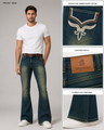 A male model wearing dark blue flared jeans with a white t-shirt and white sneakers, shown alongside three detail callout panels highlighting the signature embroidery, leather patch, and flared leg opening.