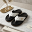 Black and white sandals on a marble surface with Fendi books and decorative items.