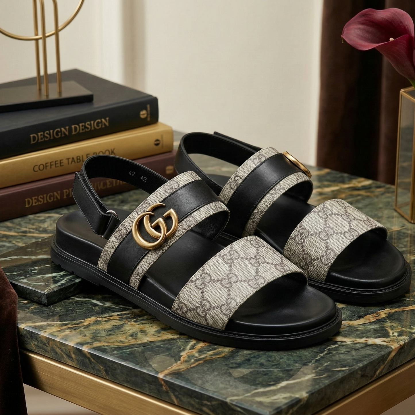 Black and white patterned sandals on a marble surface with books and a flower in the background.