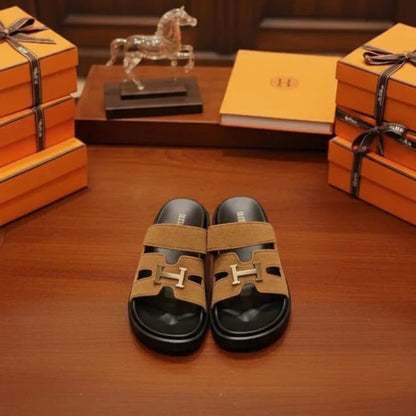 Tan sandals with black soles on a wooden surface, surrounded by orange boxes and a horse figure, with 'UNIVERSES' text above.