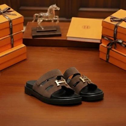 Brown sandals with gold buckles on a wooden surface with 'UNIVERSES' branding.