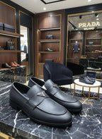 Black loafers on a marble surface with a Prada store in the background