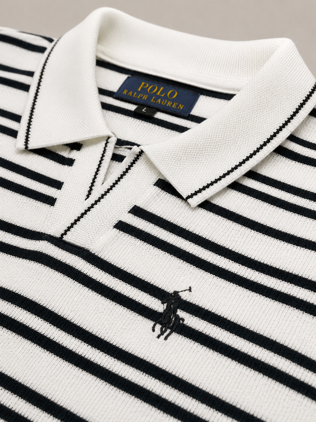 Close-up of a Polo Ralph Lauren knit polo shirt with horizontal navy and white stripes, featuring a white collar with black trim and the embroidered polo pony logo.