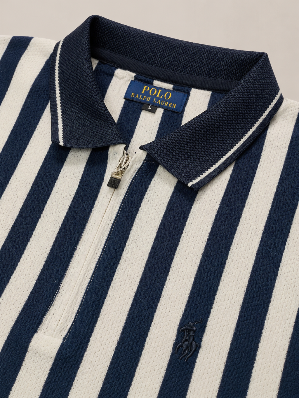 Close-up of a Polo Ralph Lauren zip-front polo shirt with navy and off-white vertical stripes, a navy collar with white piping, and a small navy embroidered pony logo on the chest.